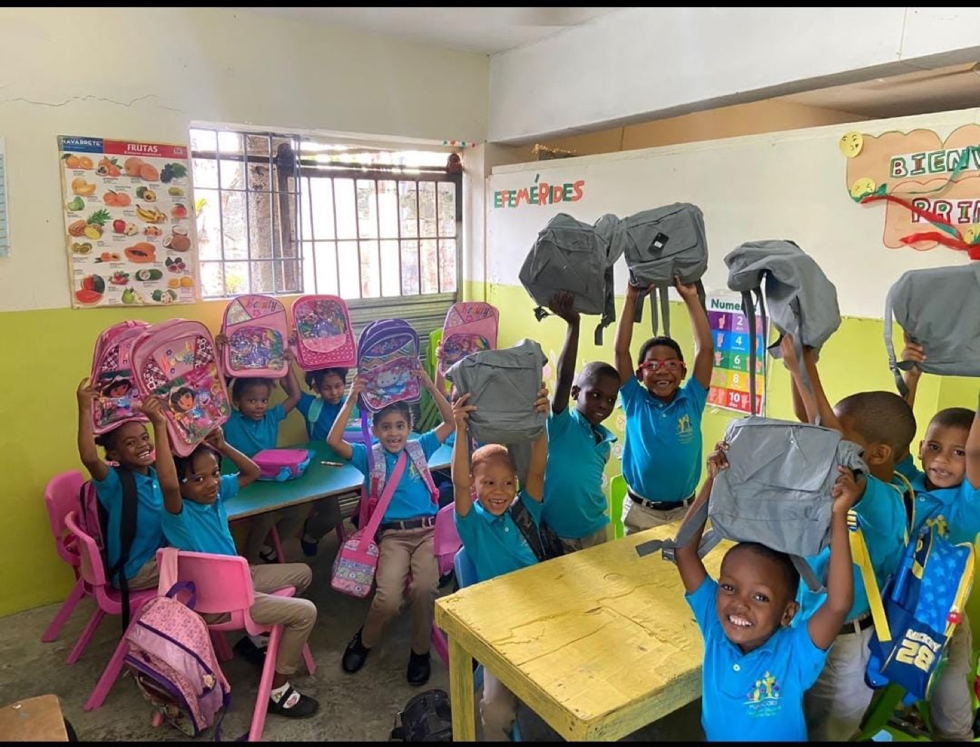 Niños de FUNACORE alzando sus mochilas nuevas